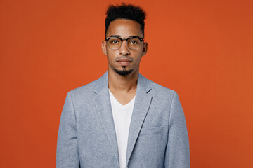 Young confident smart serious successful employee business man corporate lawyer wear classic formal grey suit shirt glasses work in office look camera isolated on plain red orange background studio.