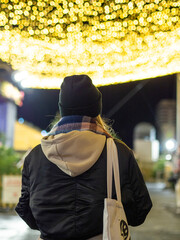 Persona con gorro de lana paseando por la calle con luces de navidad de fondo durante las fiestas