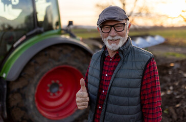 Mature farmer showing ok sign in field