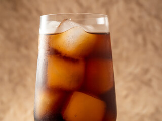 Cola with ice in a glass. Carbonated refreshing drink with ice. Cola bubbles.