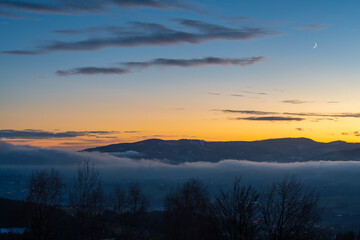 Obraz premium Winter sunset in Moravian-Silesian Beskids in Czech Republic nearby polish border, colorful sky and mountain peaks above the misty valley