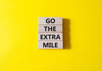 Go the extra mile symbol. Wooden blocks with words Go the extra mile. Beautiful yellow background. Business and Go the extra mile concept. Copy space.