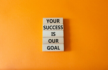 Naklejka premium Your success is our goal symbol. Wooden blocks with words Your success is our goal. Beautiful orange background. Business and Your success is our goal concept. Copy space