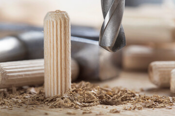drill bit makes hole in wooden oak board for wooden dowel.