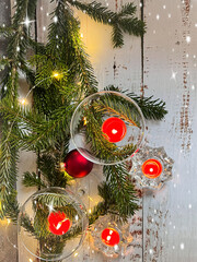 Decorative Christmas card. Champagne glasses decorated with candles on Christmas tree branches, with a garland.