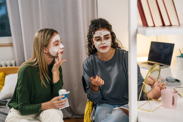 Two friends look in the mirror and put a face mask on