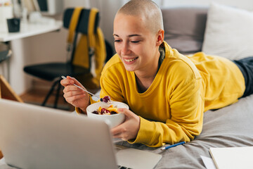 Young woman watches an online course and eats a healthy snack