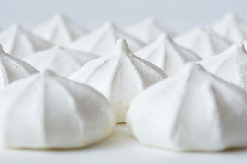 White meringues close-up on a white background, selective focus.