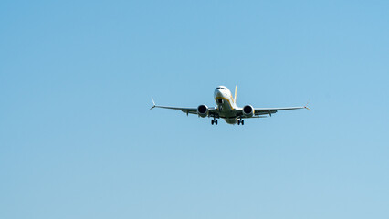 Airplane in flight, flying against the blue sky. Landing approach, landing gear down