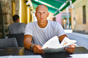 man drinking coffee and reading newspaper in cafe