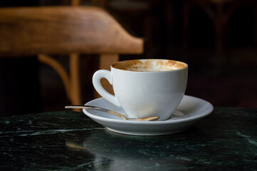 Coffee in white cup on a marble table in cafe with lighting background