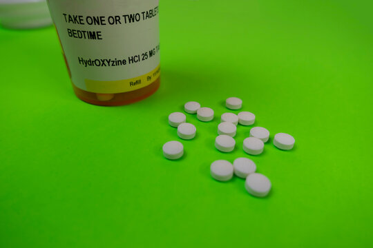 Seattle, WA USA - circa November 2022: Selective focus on Hydroxyzine pills on a green background.