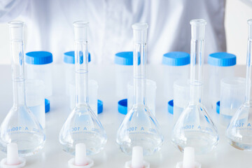 Close up laboratory glassware for analysis. Flasks and plastic bottles with blue caps for taking samples. Scientific equipment for scientific research and development.