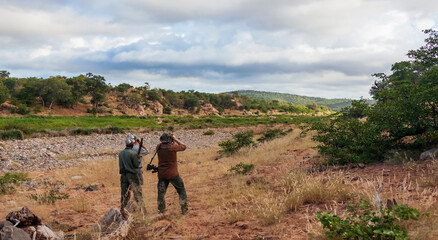  Hunter,  guide and tracker in the savannah are looking at animals in search of trophy. © okyela
