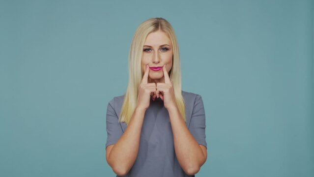 Young beautiful blond girl in the studio. Portrait of emotional girl on blue background.
