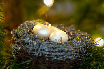 Eggs in a birds nest Christmas ornament in an artificial Christmas tree with Christmas light in background