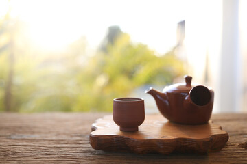 Earthenware tea pot and tea cup on wooden tray