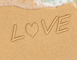 Words written in beach sand. The word LOVE written in the sand on the beach with the ocean as the background. Love is all you need. Everyone Loves the beach. Love.