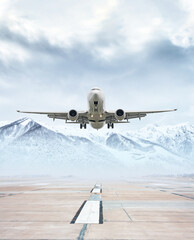 White passenger airliner take off from airport runway against the backdrop of scenic snow capped mountains