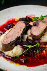 Duck fillet with mashed potatoes and blackberry sauce, closeup.