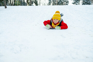Fototapeta na wymiar Boy sledding in winter forest. Winter holidays.
