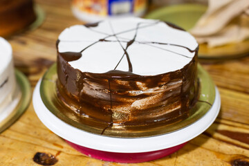 Chocolate cake with icing on wooden background. Small baking business.

