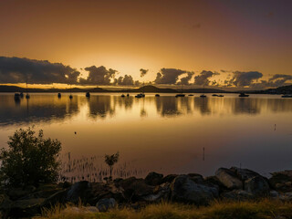 Aerial sunrise waterscape with boats and clouds in soft rose gold