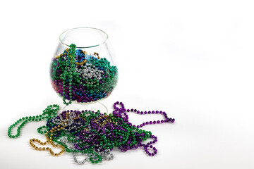 Glass crystal brandy glass filled with colorful mardi gras beads isolated on white
