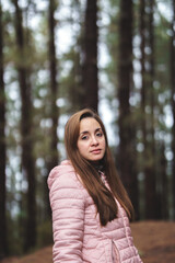 Naklejka premium portrait of a woman in the middle of the forest wearing a pink jacket and brown hair