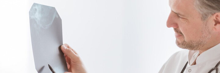 Fototapeta premium Doctor examining lung's x-ray at bright hospital office