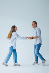 Photo of happy couple wearing white shirts, blue jeans, isolated white background. A man and a woman are hugging on a white background
