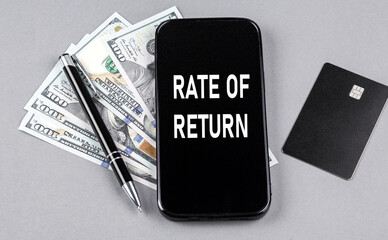Credit card and text RATE OF RETURN on smartphone with dollars and pen. Business concept