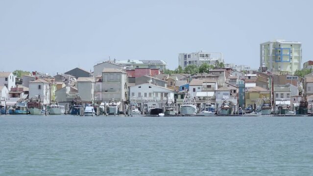 View from the lagoon on the city of Sottomarina with fish boats moored on the shore