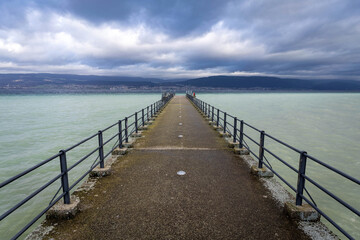Fototapeta na wymiar Ponton sur le lac de Neuchâtel avec en arrière plan le le Jura et la ville de Neuchâtel