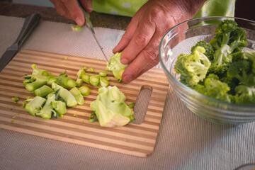 Male hands cutting healthy broccoli cabbage on wooden cutting board. Healthy eating concept