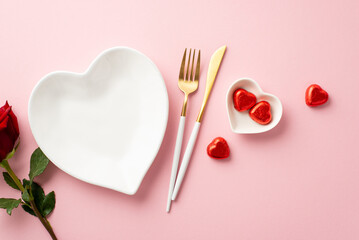 Valentine's Day concept. Top view photo of heart shaped dish cutlery chocolate candies and rose on...