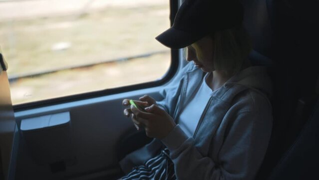 Teenage girl with smartphone travelling inside the train.