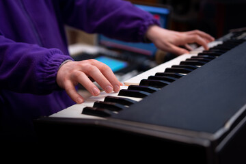 Fototapeta premium Male musician playing midi keyboard in recording studio, focus on hands. Music production