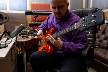 Male musician playing bass guitar in recording studio