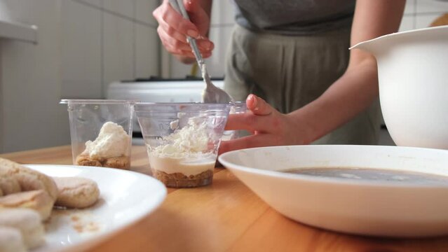 the process of cooking tiramisu. the cook lays out and smears mascarpone on the rows of savoiardi, ladyfinger (biscuit), sponge fingers, boudoirs, baby fingers. mascarpone in tiramisu