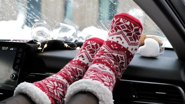 Woman feet in red knitted socks on car dashboard 