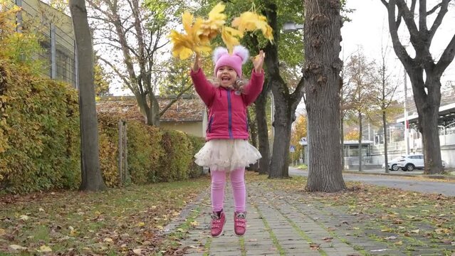 Slow motion, a girl tosses yellow maple leaves on 