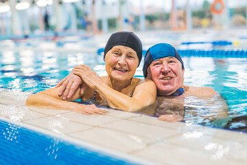 Senior couple hugging together in the swimming pool . High quality photo