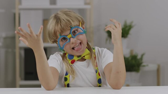 Funny girl of 7 years dressed in clown eye glasses, butterfly and suspenders.
