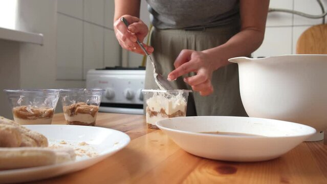 the process of cooking tiramisu. the cook lays out and smears mascarpone on the rows of savoiardi, ladyfinger (biscuit), sponge fingers, boudoirs, baby fingers. mascarpone in tiramisu