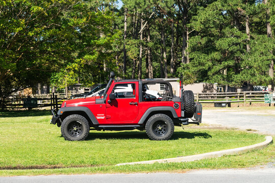Jeep Wrangler sport red color parked on the green lawn in the park
