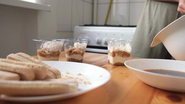the process of cooking tiramisu. the cook lays out and smears mascarpone on the rows of savoiardi, ladyfinger (biscuit), sponge fingers, boudoirs, baby fingers. mascarpone in tiramisu