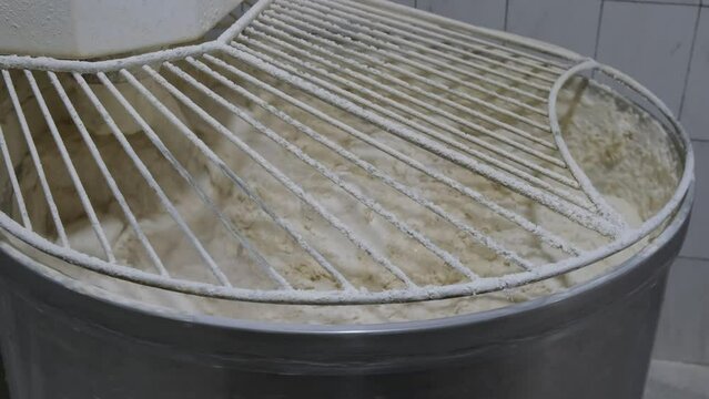 4k v&iacute;deo. Slow motion de m&aacute;quina mezcladora de pan gigante en una panader&iacute;a amasando masa con harina volando