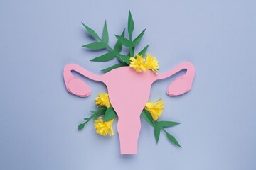 Woman's health. Paper uterus and flowers on light blue background, flat lay