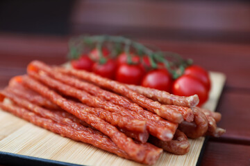 Tasty dry cured sausages (kabanosy) on wooden table, closeup